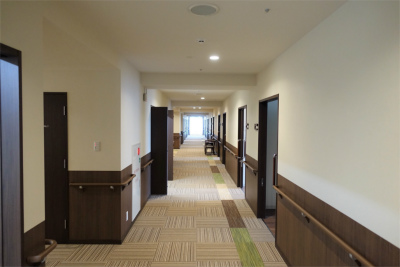 共用の廊下には絨毯が敷いてあり、転倒予防になります。両側にお部屋が並んでいます。